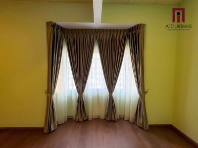 A room with an olive wall, brown drapes tied back at both sides of a corner window and a white sheer behind them.